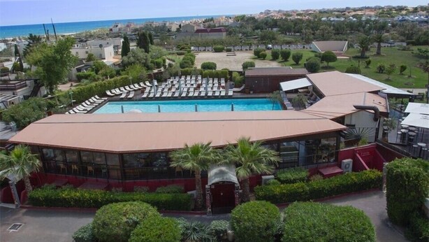 Een hotel met een zwembad, ligbedden en uitzicht op zee.