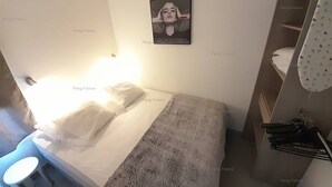 Um quarto com cama, mesa de cabeceira, toalha, quadro na parede e guarda-roupa.