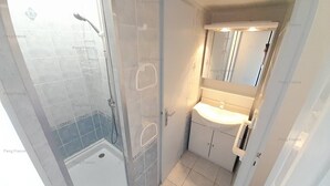 Un bagno con doccia, lavandino e specchio.