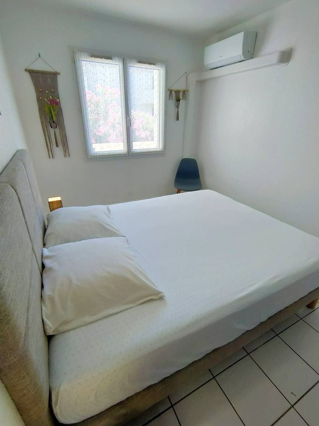 Camera singola con un letto, una finestra, una sedia e condizionatore d'aria a parete.