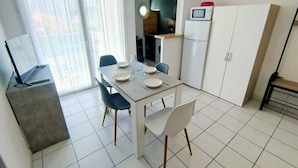 A modern kitchen with white cabinets, a microwave, and a dining area with a table and chairs. - Bright one-bedroom apartment, air conditioning and parking - 4VOIL245 (CANET PLAGE)