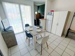 A modern kitchen with white cabinets, a microwave, and a dining area with a table and chairs.