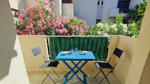 A small outdoor patio with a blue table and two chairs, surrounded by a low wall and a variety of plants. - Bright one-bedroom apartment, air conditioning and parking - 4VOIL245 (CANET PLAGE)
