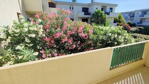 A balcony with a flower bed, a green mesh screen, and a tiled floor. - Bright one-bedroom apartment, air conditioning and parking - 4VOIL245 (CANET PLAGE)