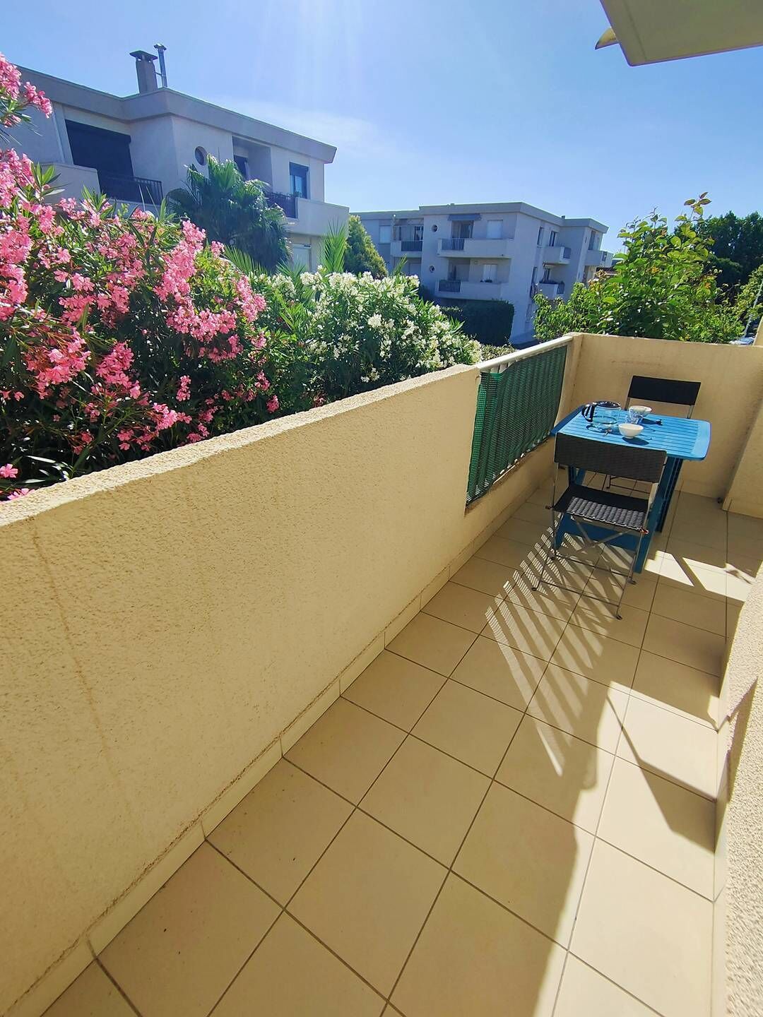 A balcony with a tiled floor, a table with chairs, and a view of neighboring buildings.