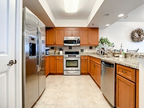 Kitchen features an oven, microwave, and dishwasher, with a granite countertop and tiled floor.
