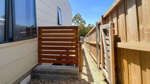 A wooden gate leading to a building with large windows.