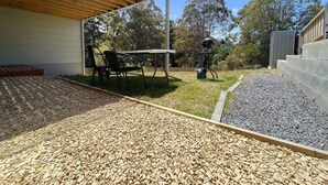 A patio area with a table and chairs, a grill, and a wooden deck.