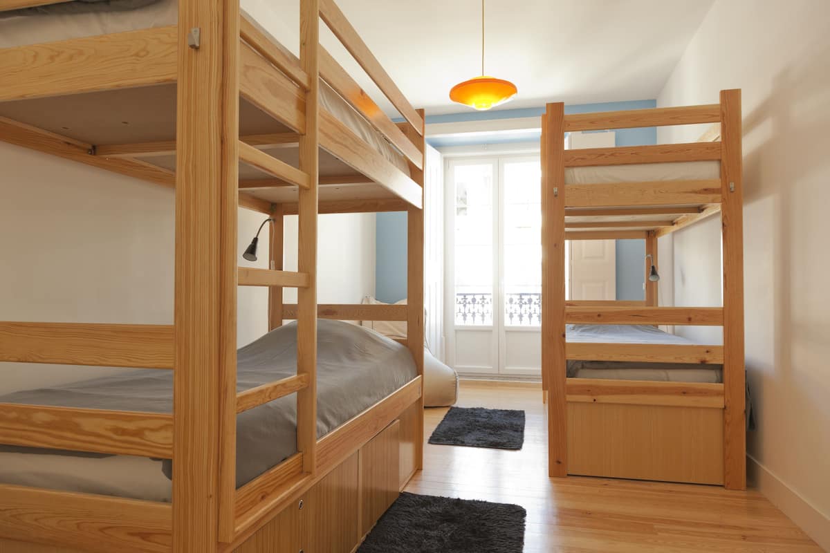 A room with bunk beds, a black rug, and a hanging light fixture.