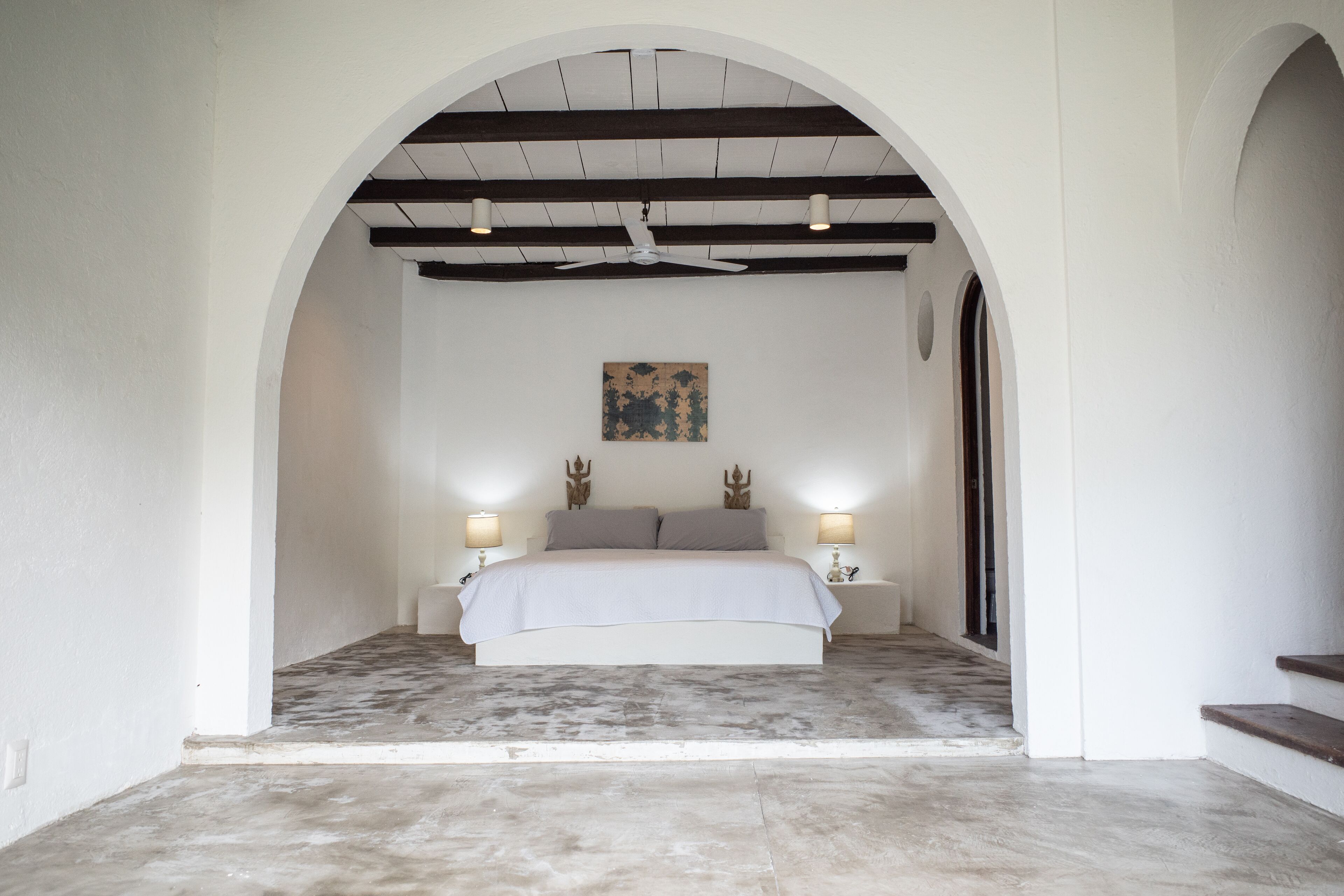Une chambre à coucher avec un lit placé au centre, sous un plafond en arc, et flanqué de deux tables de chevet sur lesquelles sont posées des lampes.