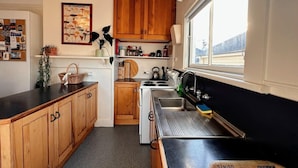 A compact kitchen with wooden cabinets, a stove, and a sink.