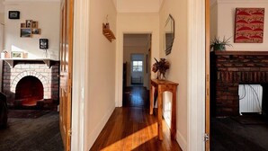 A hallway with a fireplace, a wooden floor, and a door leading to another room.