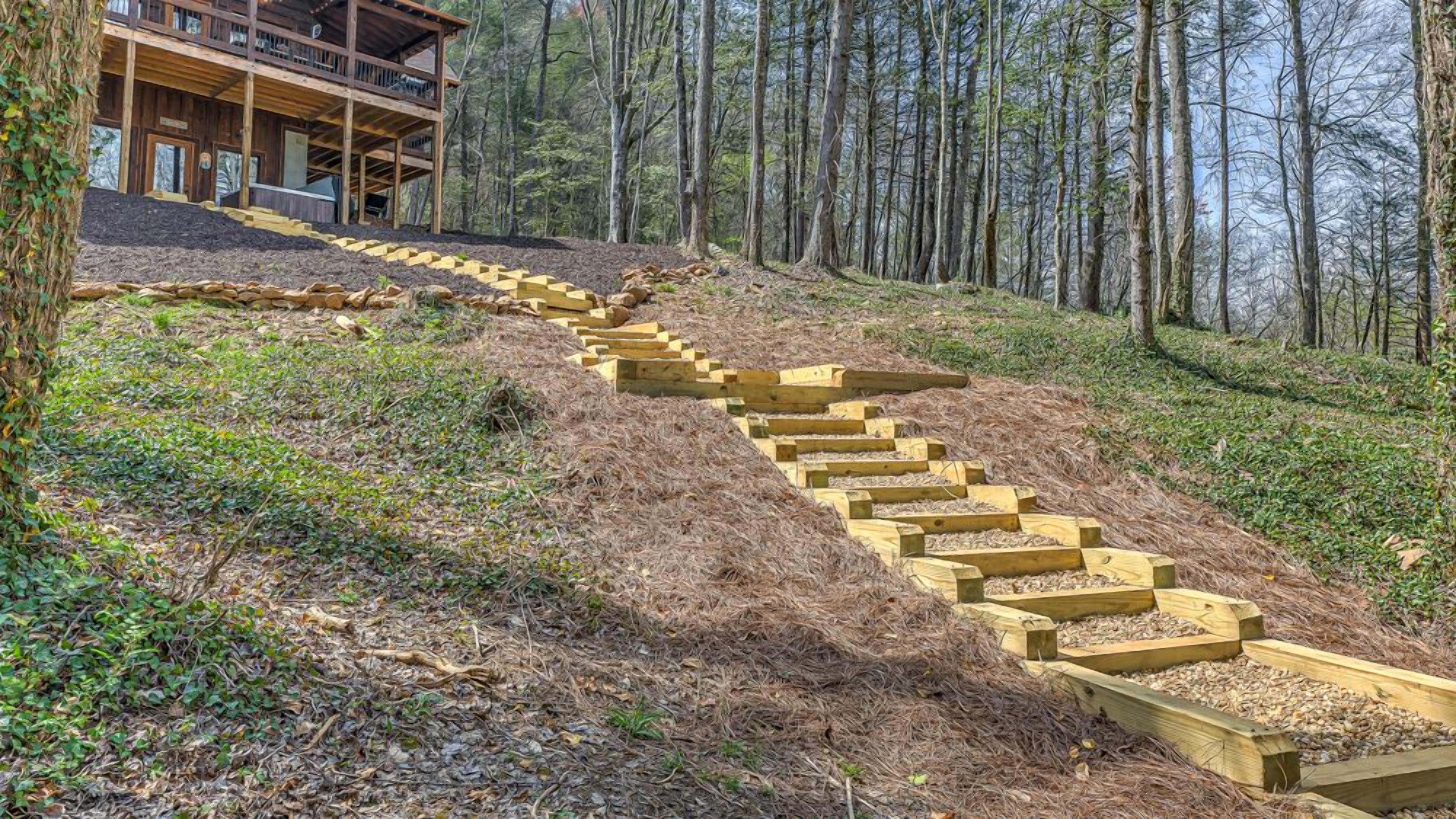 A wooden staircase leading up a hill, surrounded by trees.