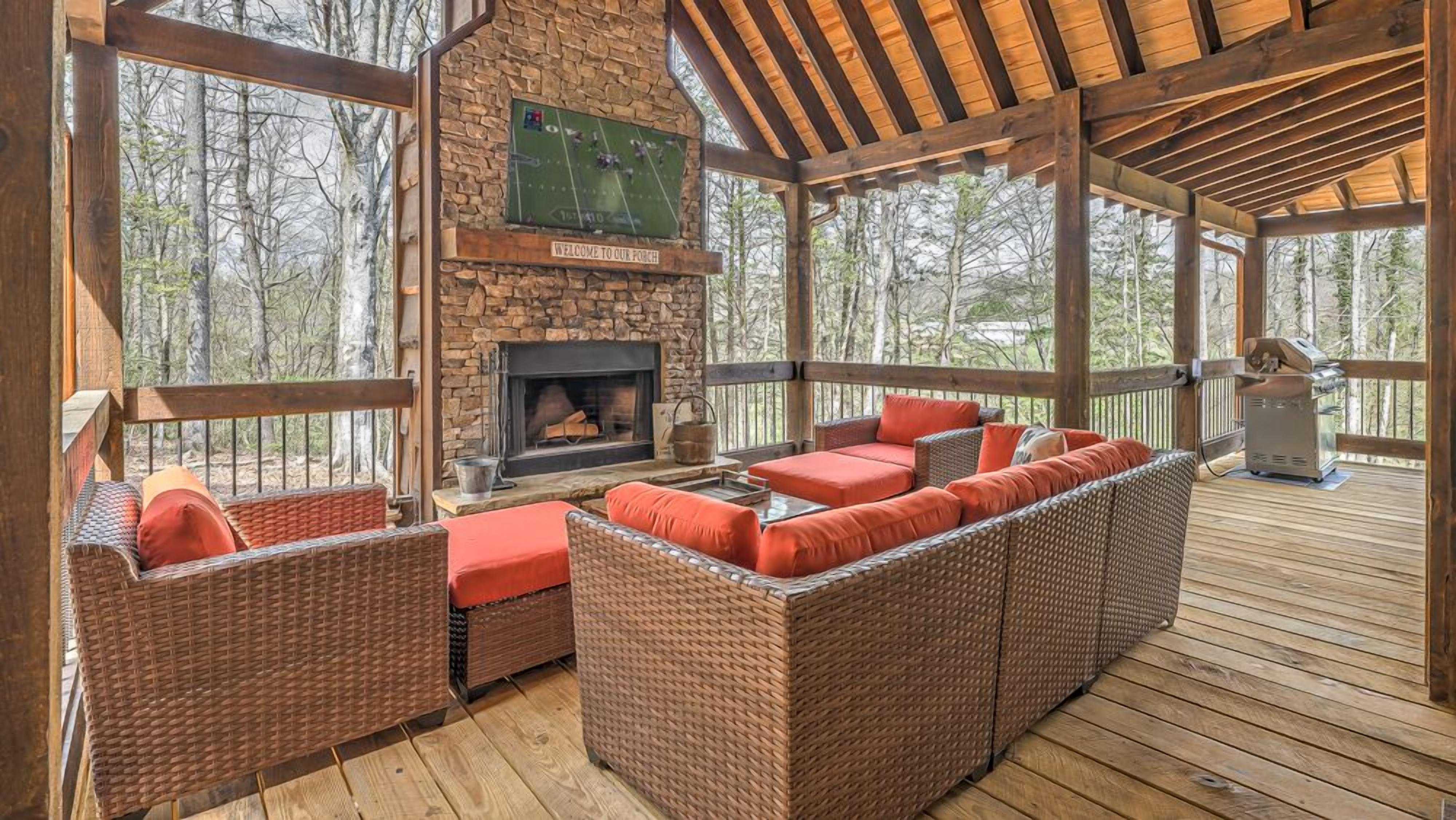 A covered outdoor seating area with wicker furniture and a stone fireplace.