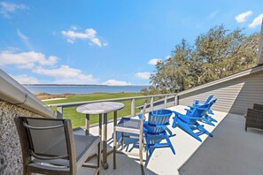 A balcony with a view of the ocean, a table, and blue chairs. - Luxurious Harbour Town Villa with a stunning patio space overlooking the water and golf course! (Hilton Head Island)