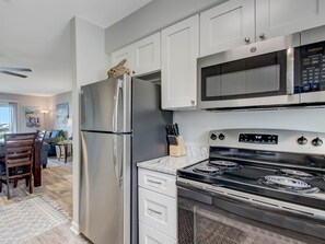 A modern kitchen with stainless steel appliances, white cabinetry, and a marble countertop.