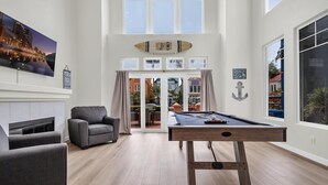 Um quarto espaçoso com mesa de bilhar, um sofá confortável e lareira.