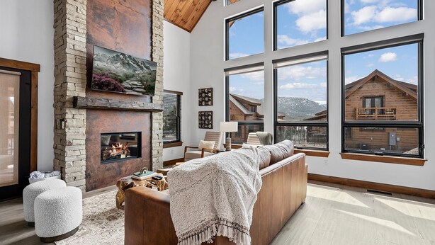 Un salon spacieux doté d’une cheminée, de grandes fenêtres et offrant une vue sur un chalet en bois.