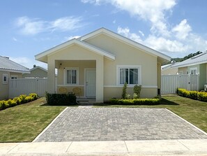 A single-story house with a front porch, a driveway, and a well-maintained lawn.