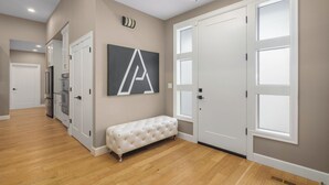 A hallway with a bench, a large wall-mounted sign, and a door with a window. - Large Open Home - Gourmet Kitchen - Pool Table (Portland)