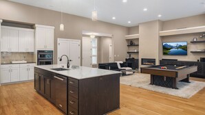 A modern kitchen with a large island, built-in appliances, and a pool table. - Large Open Home - Gourmet Kitchen - Pool Table (Portland)