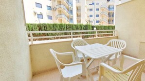 A balcony with a table and chairs, a view of a building with balconies, and a hedge in the background. - Apartment 150 meters from the beach, 500 meters from Denia (Denia)