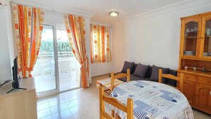 A room with a dining table, chairs, a sofa, a cabinet with glass doors, and a television. - Apartment 150 meters from the beach, 500 meters from Denia (Denia)