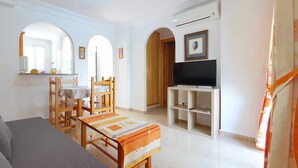 A living room with a sofa, a small table, and a TV stand. There are wooden chairs and a dining table with chairs. - Apartment 150 meters from the beach, 500 meters from Denia (Denia)