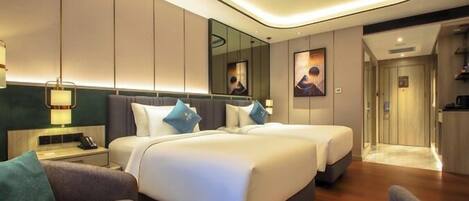 A modern hotel room with two beds, a sitting area, and a bathroom.
