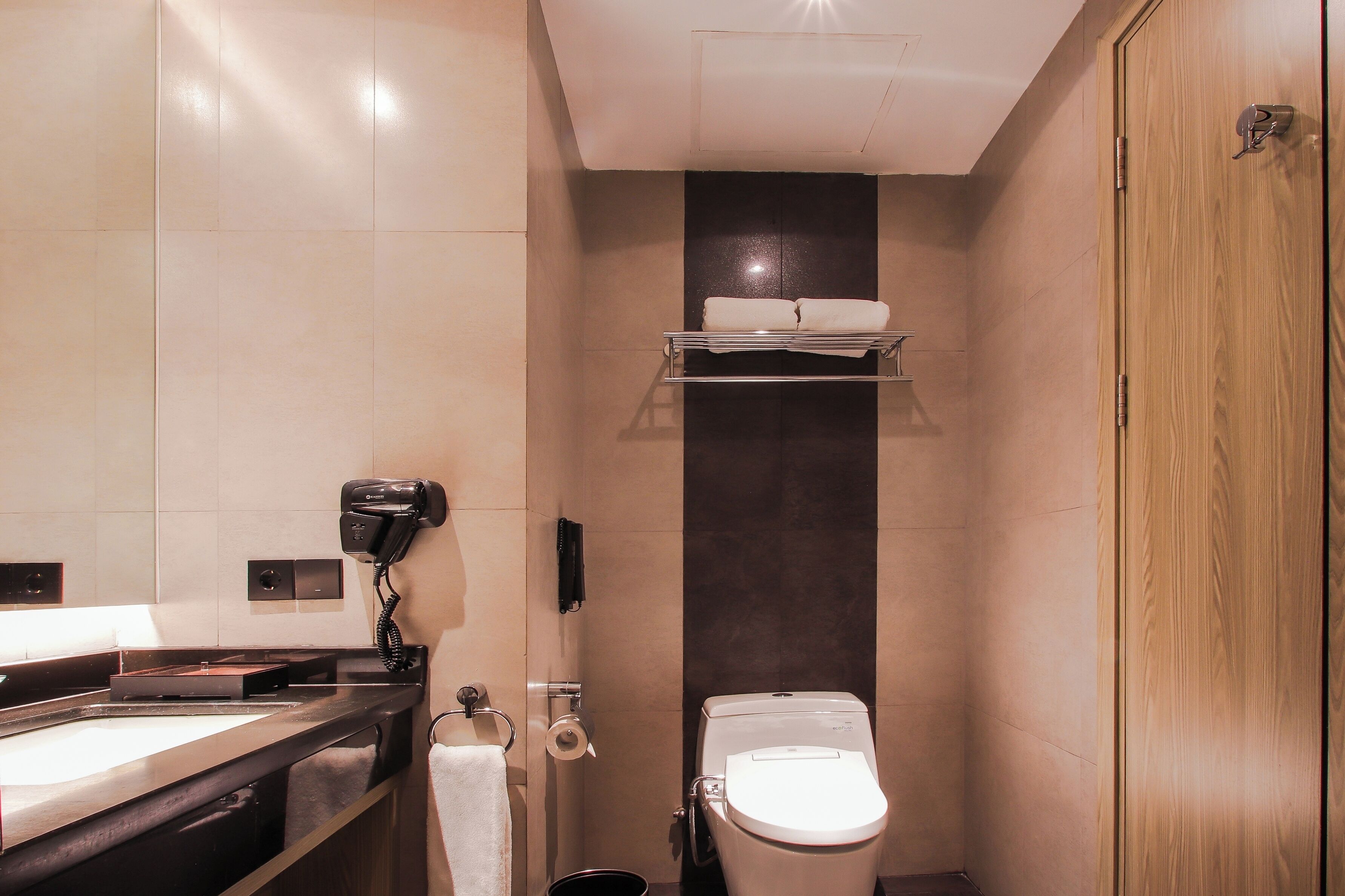 A compact bathroom with a toilet, a sink, a hairdryer, and a towel rack.