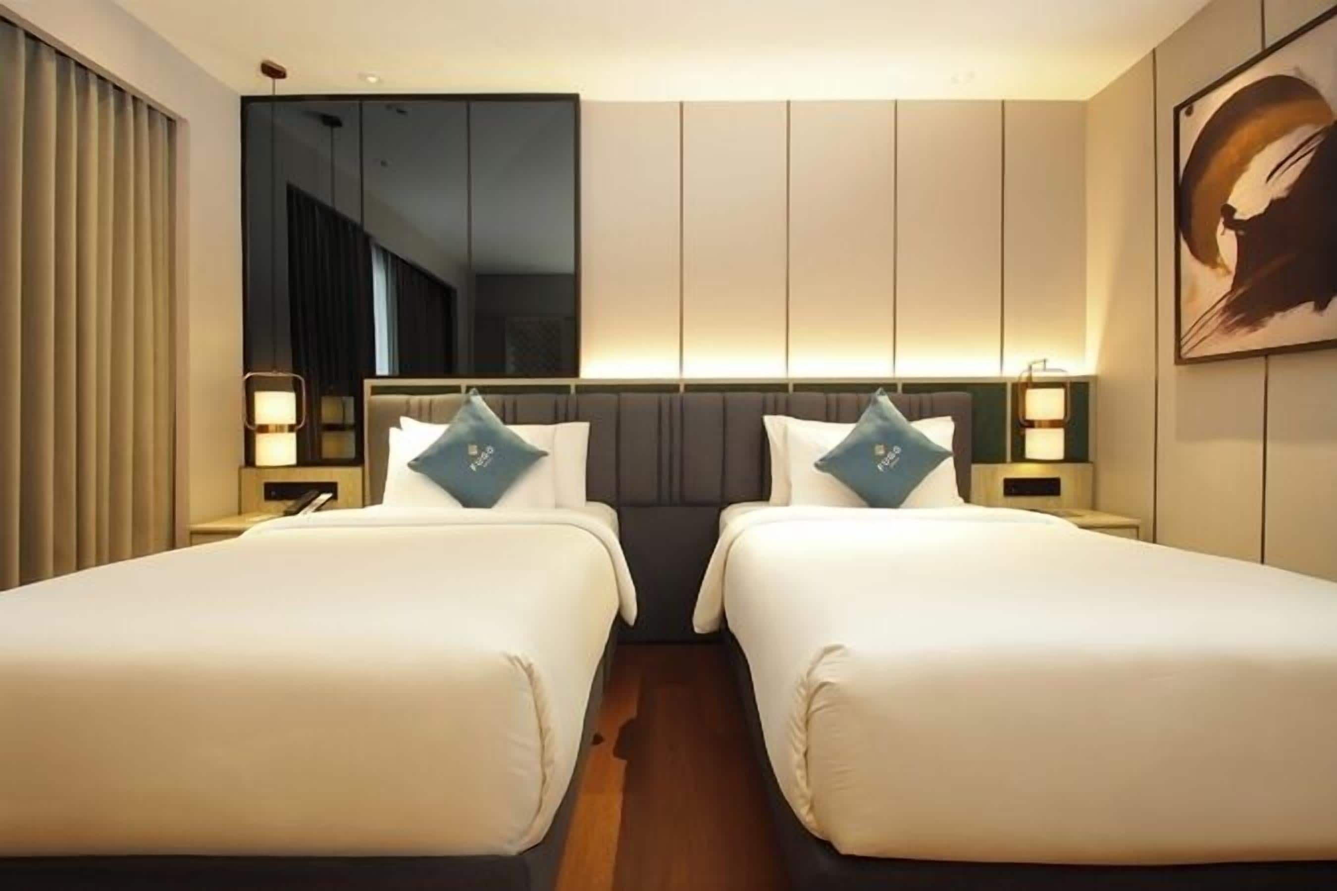 Quarto de hotel com duas camas, um espelho grande e um quadro na parede.