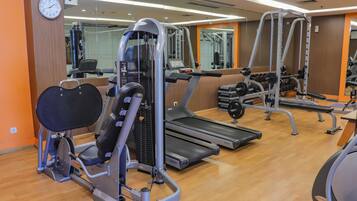 Un gimnasio con equipo cardiovascular, máquinas de pesas y mancuernas.