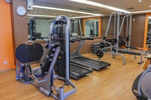 Un gimnasio con equipo cardiovascular, máquinas de pesas y mancuernas.