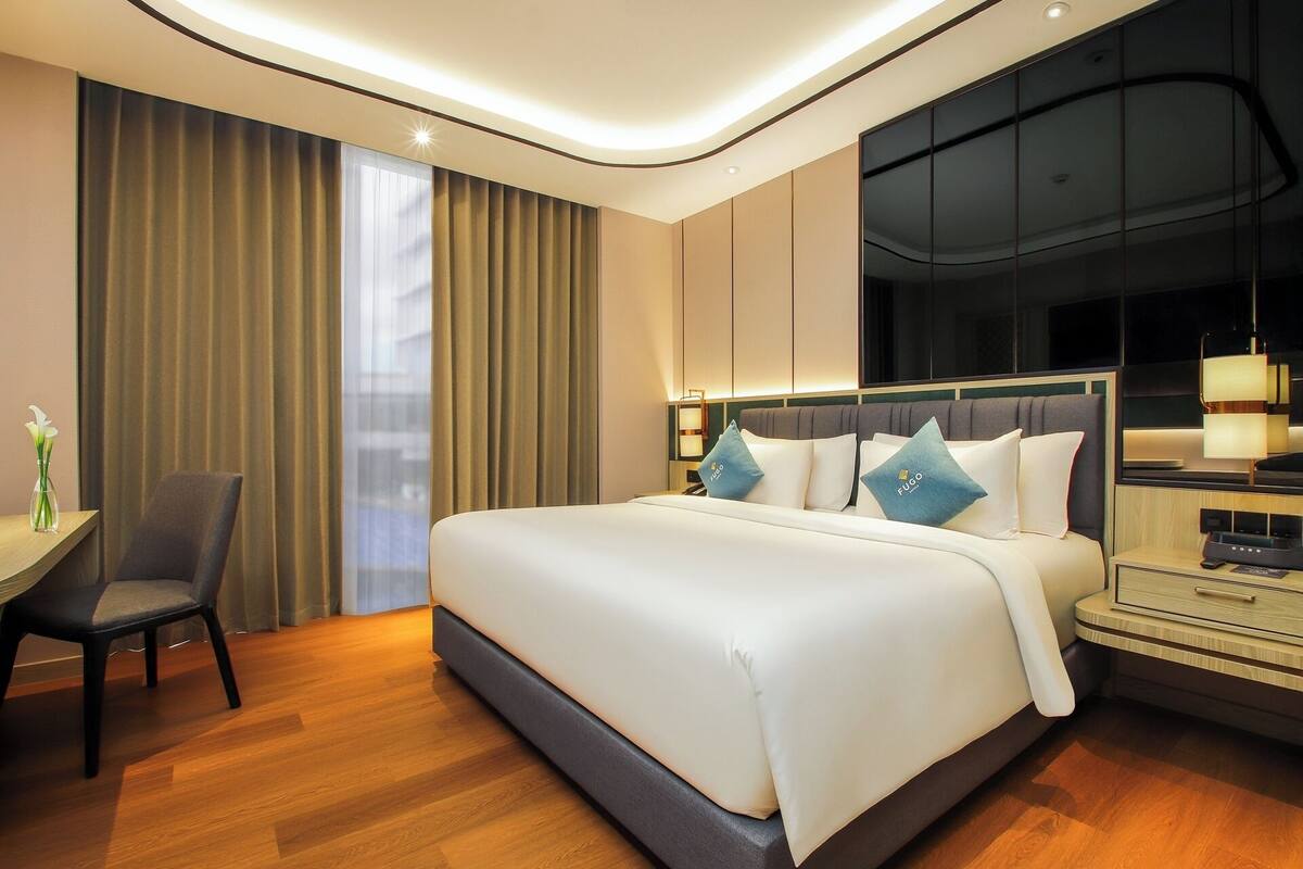 A modern hotel room with a large bed, a desk, and a chair.