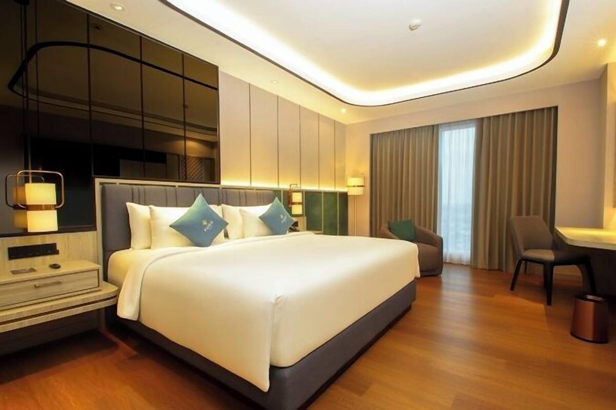 A modern hotel room with a large bed, bedside tables, a desk, and a chair.