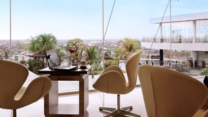 Una habitación moderna con vistas a la ciudad, un escritorio con una computadora portátil y dos sillas.