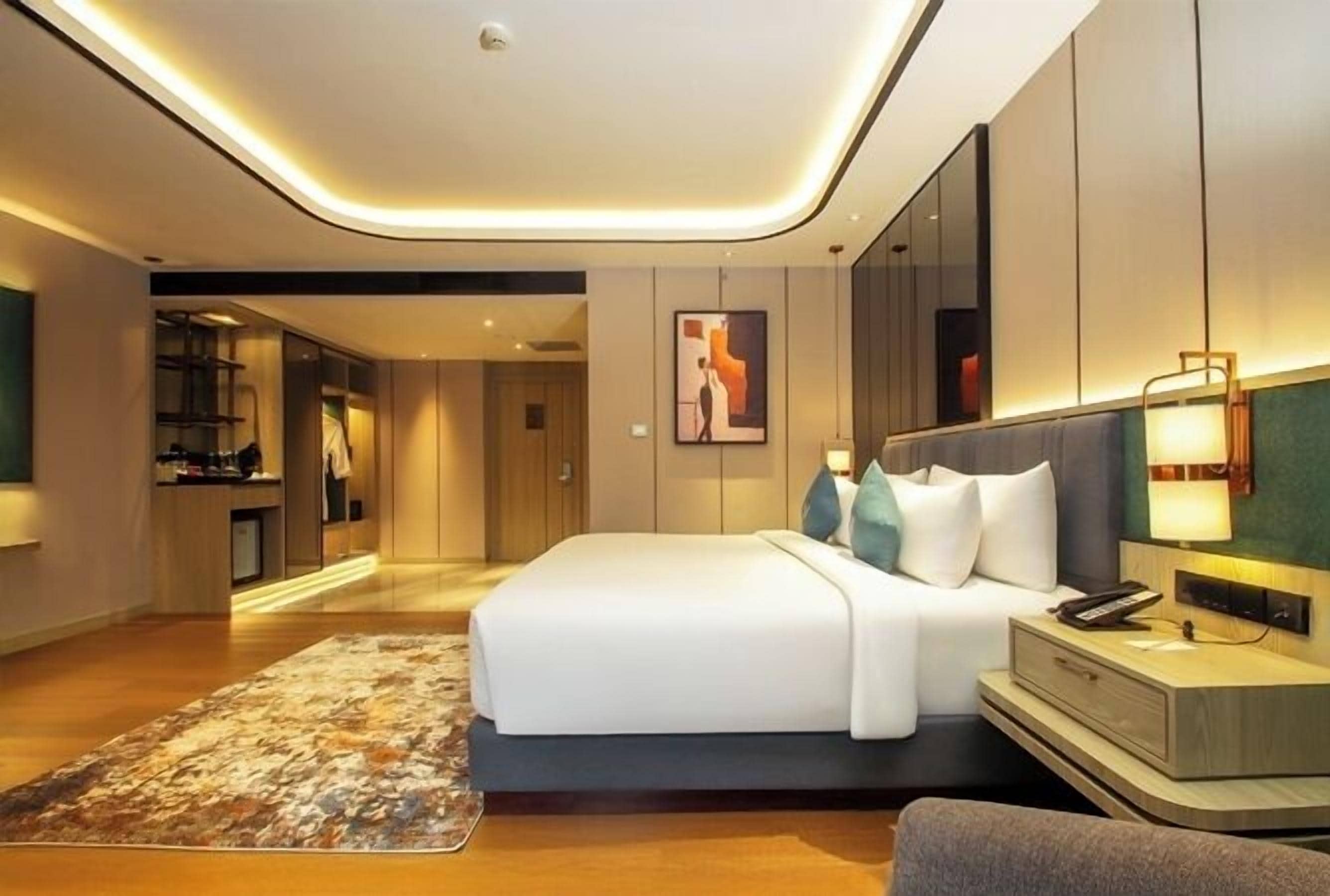 Een moderne hotelkamer met een groot bed, nachtkastjes, een bureau en een badkamer zichtbaar door een geopende deur.