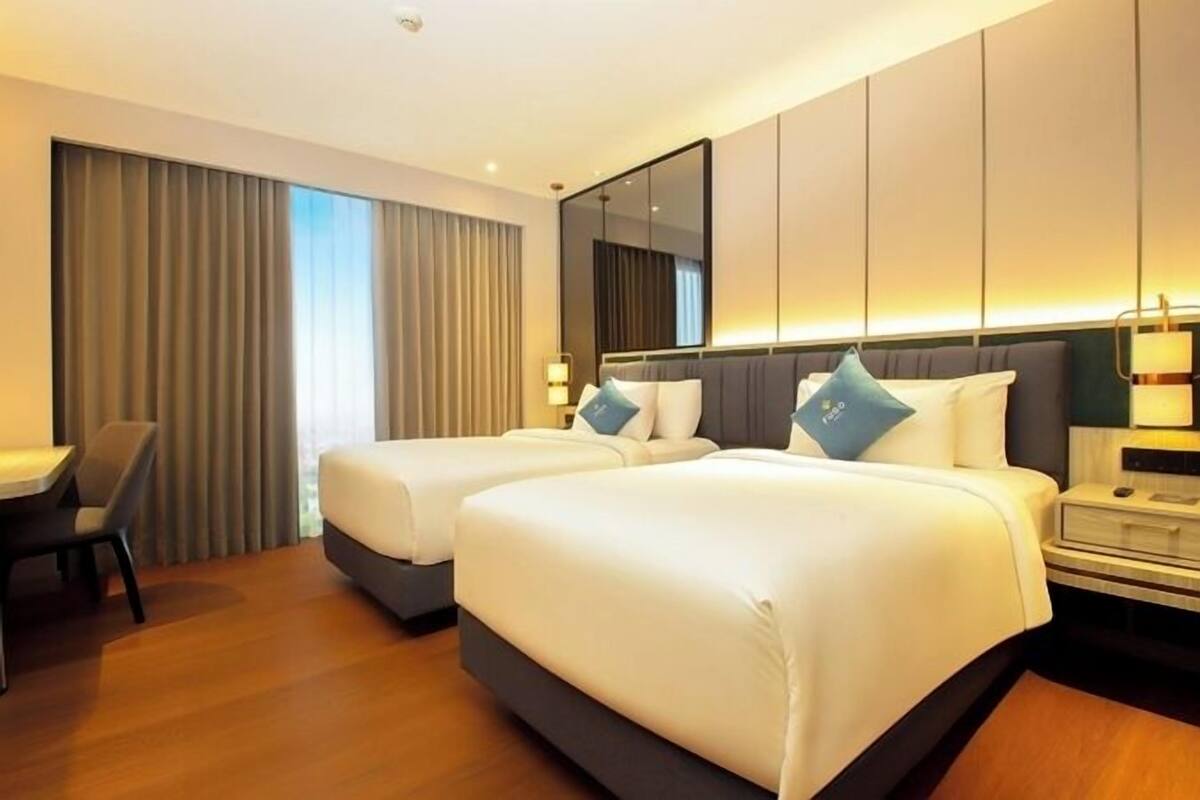 A hotel room with two beds, a desk, and a chair.