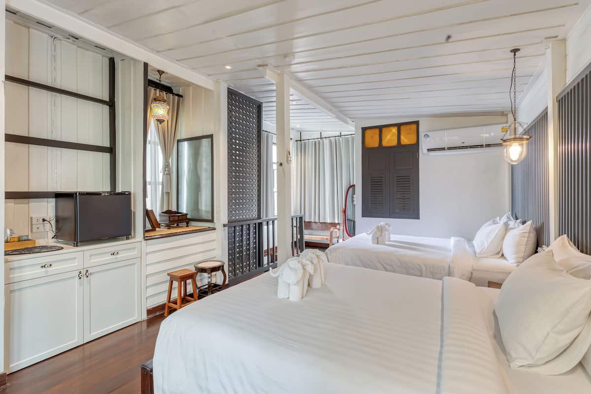 Hotelkamer met een groot bed, een bureau, een flatscreen-televisie, een klein krukje en een raam met gordijnen.