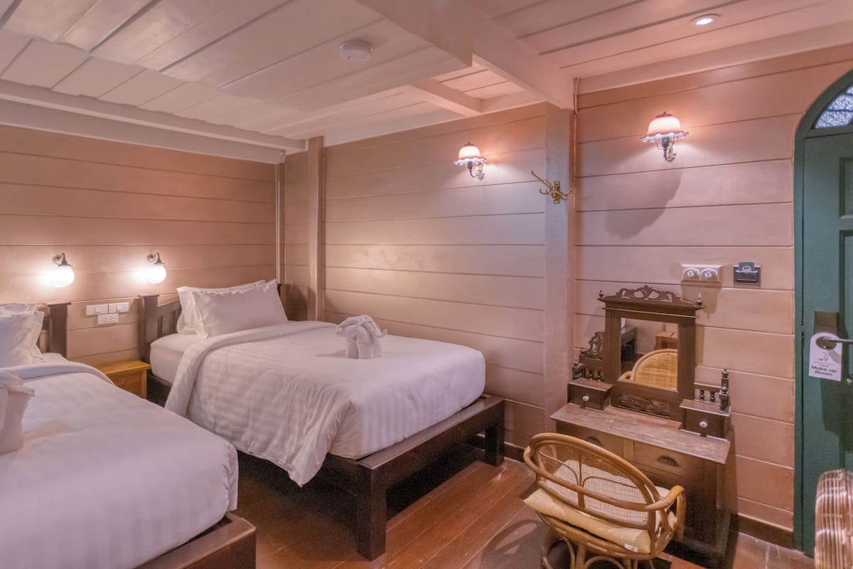 Een hotelkamer met twee bedden, een houten hoofdbord, een klein tafeltje met spiegel en wandlampen.