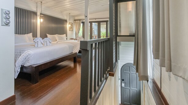 A bedroom with a wooden bed, a balcony with a railing, and a view of the outside. - Priya Boutique House (Bangkok)