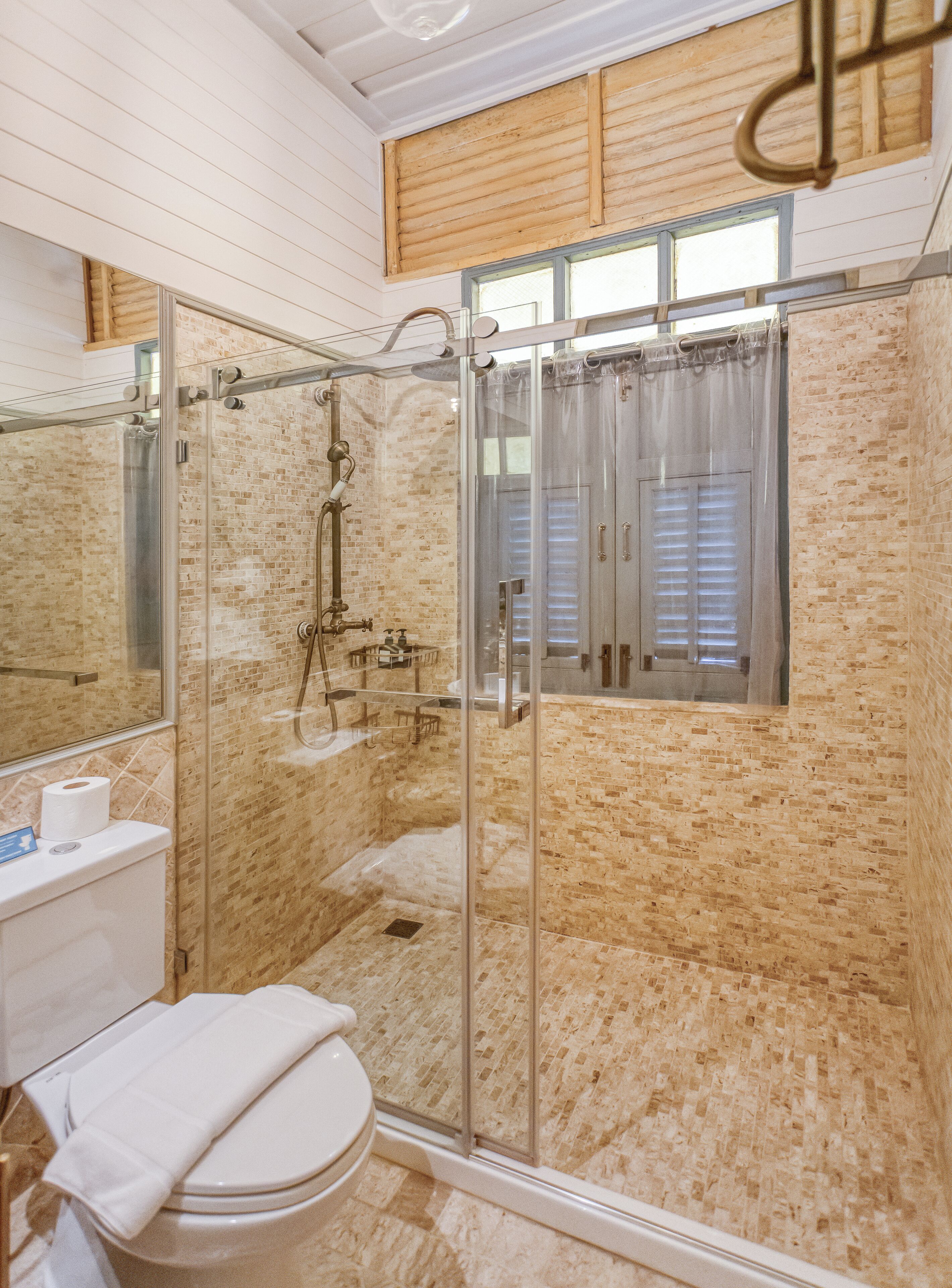 A bathroom with a glass-enclosed shower, a toilet, and a sink.