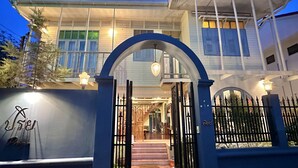 A two-story house with a gated entrance, a covered porch, and a visible staircase leading to the entrance. - Priya Boutique House (Bangkok)