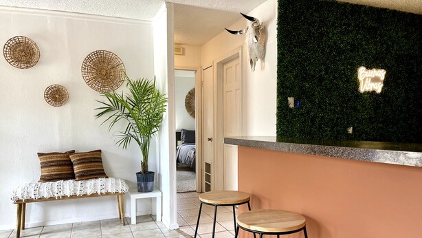 A cozy living area with a bench, stools, a potted plant, decorative wall hangings, and a wall-mounted animal skull. - Trendy&Cute4BR+Pool-NearStMary’sUniversity&DTSA! (San Antonio)