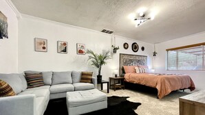 A modern bedroom with a grey sofa, a bed with a patterned headboard, and a black and white rug. - Trendy&Cute4BR+Pool-NearStMary’sUniversity&DTSA! (San Antonio)