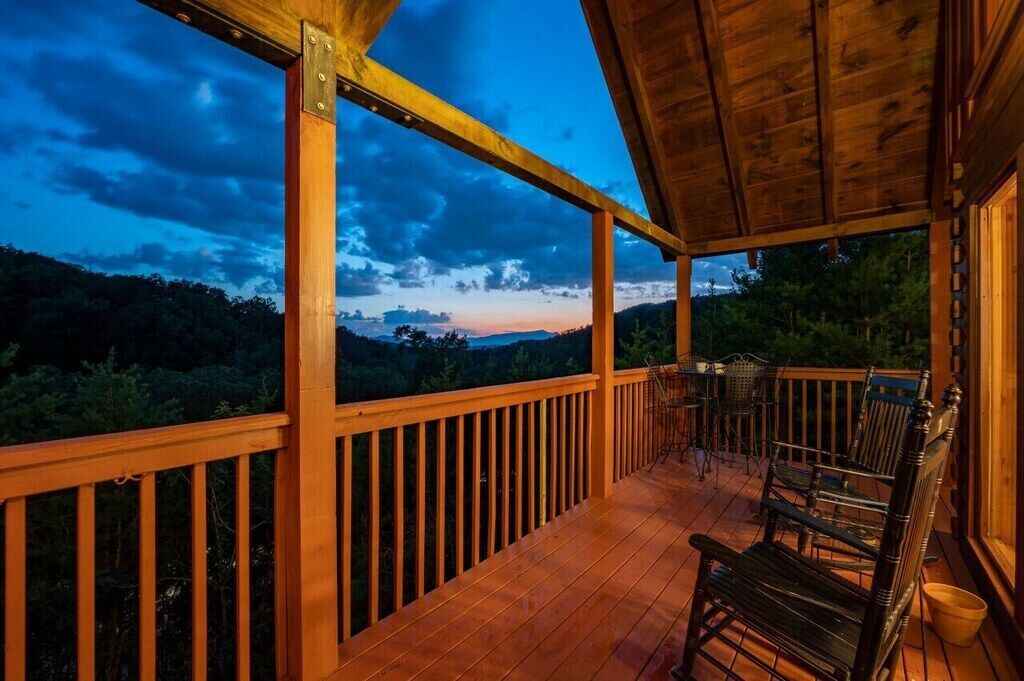 Une terrasse en bois avec une rambarde, une table et deux chaises.