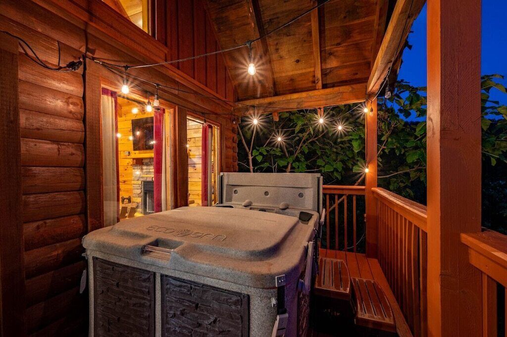 A hot tub on a wooden deck with string lights.