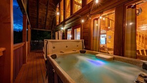 Een houten wellnessruimte met een bubbelbad, een houten terras en sfeerverlichting.