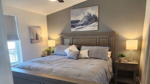 Un dormitorio con una cama grande, dos mesitas de noche con lámparas, una ventana con persianas y un cuadro en la pared.