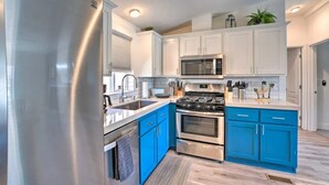 Una cocina moderna con electrodomésticos de acero inoxidable, armarios azules y encimera blanca.